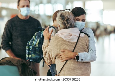 Mother Embracing Her Daughter And Grandson At Airport Arrival Gate. Woman With Her Son Giving Hug To Her Mother At Airport In Pandemic.