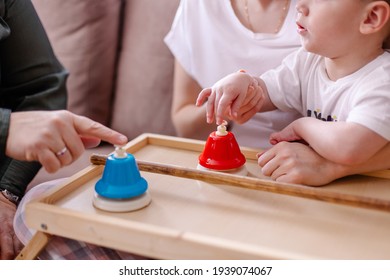 A Mother Is Engaged In A Music Lesson With Her Child With Cerebral Palsy. Rehabilitation With Musical Instruments. Hands With Hypertonicity With Bells Close-up. Disability