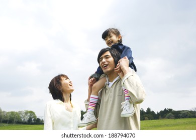 mother escorting to father with their daughter on his shoulders in prairie