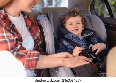 Madre sujetando a su hijo en el asiento de seguridad infantil dentro del auto