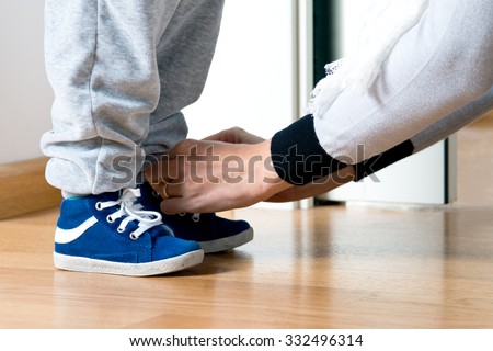 Mother fastens the shoe of his child