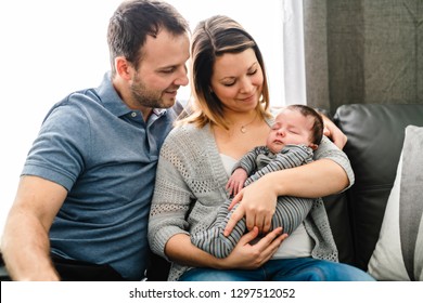 Mother and father with baby having greet time on the sofa at home - Shutterstock ID 1297512052