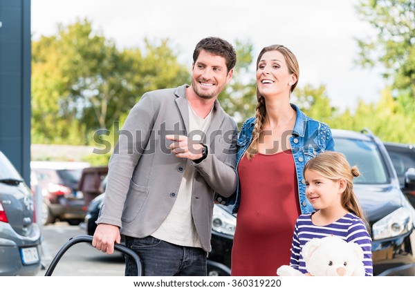 Mother, father, and child buying car at dealership,\
a new family auto