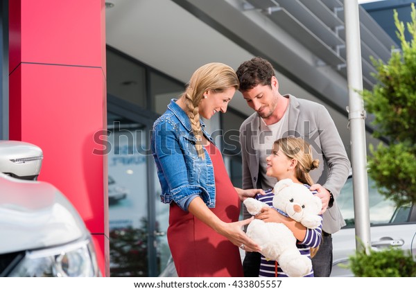 Mother, father, and child buying car at dealership,
a new family auto