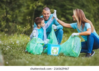 Mother, father and child collect garbage to clean the forest. They are in nature together and collect garbage in bags. The concept of ecology and recycling - Powered by Shutterstock