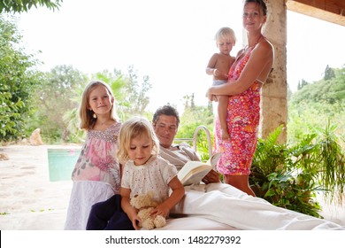 Mother, Father, Children In Home Swimming Pool Garden Relaxing Together, Smiling Outdoors. Beautiful Family Bonding Enjoying Holiday Villa, Summer Travel Abroad, Weekend Leisure Recreation Lifestyle.