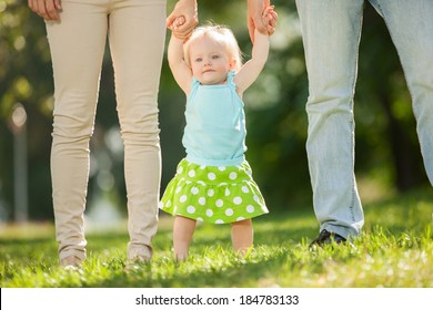 Mother, father and daughter in the park. First steps
