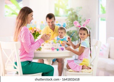 Mother, Father And Kids Color Easter Eggs. Mom, Dad, Little Girl And Boy With Bunny Ears Dying And Painting For Easter Egg Hunt. Family And Child Celebration. Home Decoration For Spring Holiday.