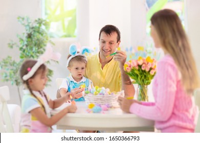 Mother, Father And Kids Color Easter Eggs. Mom, Dad, Little Girl And Boy With Bunny Ears Dying And Painting For Easter Egg Hunt. Family And Child Celebration. Home Decoration For Spring Holiday.