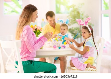 Mother, Father And Kids Color Easter Eggs. Mom, Dad, Little Girl And Boy With Bunny Ears Dying And Painting For Easter Egg Hunt. Family And Child Celebration. Home Decoration For Spring Holiday.