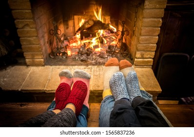 Mother Father And Kids Sitting At Cosy Fireplace On Christmas Time - Lovely Family Resting Together On Woolen Socks At Home Fire Place - Winter Holiday And X Mas Concept On Comfy Warm Flame Filter