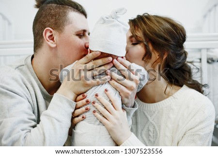 mother and father are kissing their baby