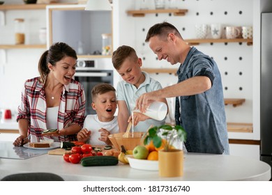  Mother And Father Making Breakfast With Sons. Young Family Preparing Delicious Food In Kitchen