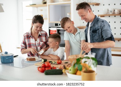  Mother And Father Making Breakfast With Sons. Young Family Preparing Delicious Food In Kitchen