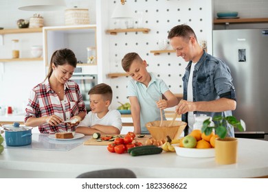  Mother And Father Making Breakfast With Sons. Young Family Preparing Delicious Food In Kitchen