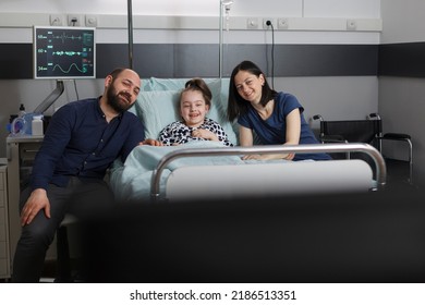 Mother and father resting with sick little girl while enjoying family tv series. Caring parents sitting beside hospitalized daughter while watching television show inside children healthcare