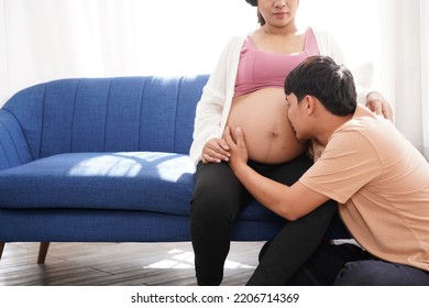 Mother And Father Are Setting Together. Dadd Listens Mom's Tummy To Hear Baby From Pregnant's Woman. New Born Baby Is Coming. Kissing Kid Though Mom's Tummy,