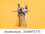 A mother and father share a joyful interaction with their teenage daughter as they embrace each other in a loving and playful manner, highlighting their strong family bond.