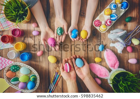 A mother, father and their child painting eggs. Happy family preparing for Easter.