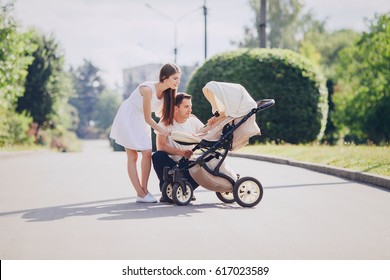 mother and father walk through the park with daughter in stroller