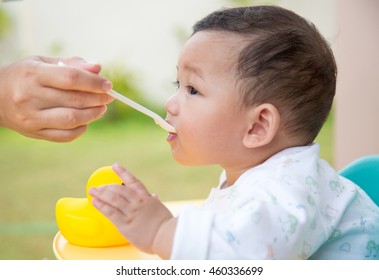 Mother Feeding A Baby. Asian Boy