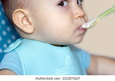 Mother Feeding Baby Boy With Mashed Food Puree Yogurt Healthy Diversification.toddler In High Chair Side View Green Silicone Spoon.wide Open Mouth Hungry Boy.wide Banner Child With Spoon In Hand.dirty