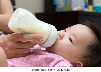 Mother feeding baby with milk from a bottle