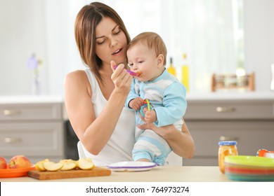 Mother Feeding Baby With Spoon Indoors