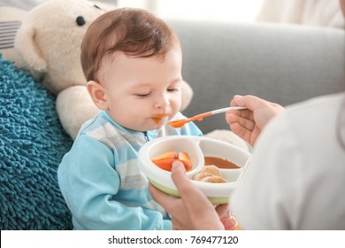 Mother Feeding Baby With Spoon Indoors