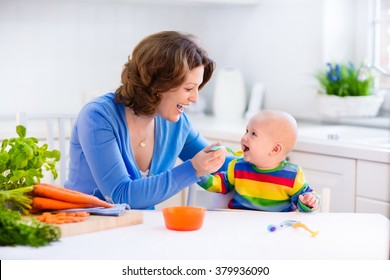 Mother Feeding Child. First Solid Food For Young Kid. Fresh Organic Carrot For Vegetable Lunch. Baby Weaning. Mom And Little Boy Eat Vegetables. Healthy Nutrition For Children. Parents Feed Kids.