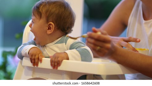 
Mother Feeding Crying Baby Infant Toddler On Highchair