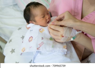 mother feeding cup of milk for newborn baby in patient room . useful when small volumes of breastmilk/colostrum are being given and during emergency situations or mother has problem with her nipple.