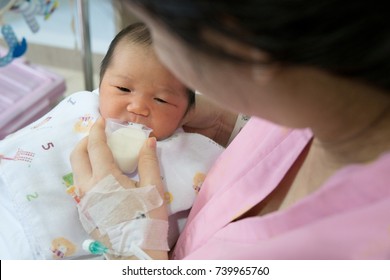 mother feeding cup of milk for newborn baby in patient room . useful when small volumes of breastmilk/colostrum are being given and during emergency situations or mother has problem with her nipple.