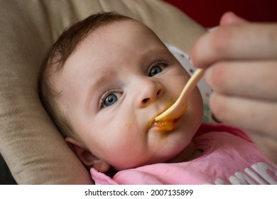 Mother Feeding Cute Baby Girl With Spoon. Child Eating Healthy Food With Messy Mouth