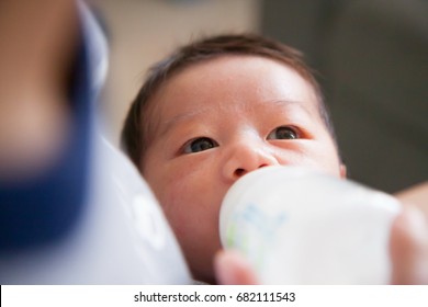 Mother is feeding her baby by using bottle.