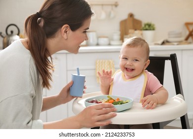 Mother feeding her cute little baby in kitchen - Powered by Shutterstock