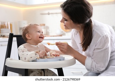 Mother feeding her cute little baby in kitchen - Powered by Shutterstock