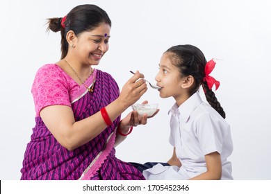 Mother feeding her daughter with curd before going to school. - Powered by Shutterstock