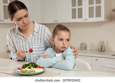 Mother feeding her daughter in kitchen. Little girl refusing to eat dinner - Powered by Shutterstock