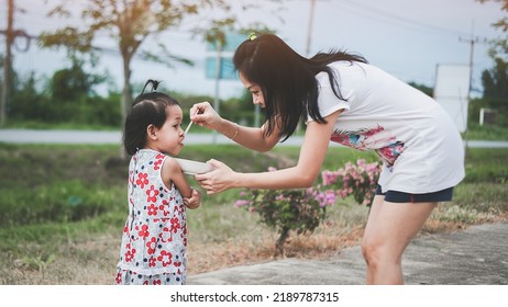 Mother Feeding Her Daughter With A Spoon. Mother Giving Food To Her Little Girl Child