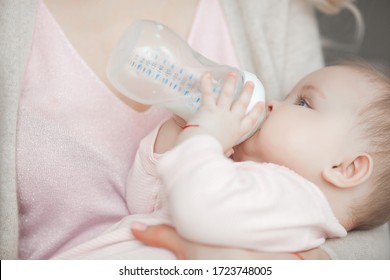 Mother Feeding Her Little Baby. Child Eating Formula.