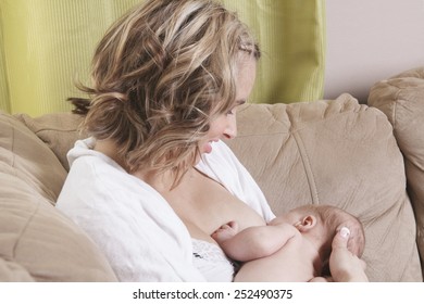 A Mother Feeding His Baby On The Sofa