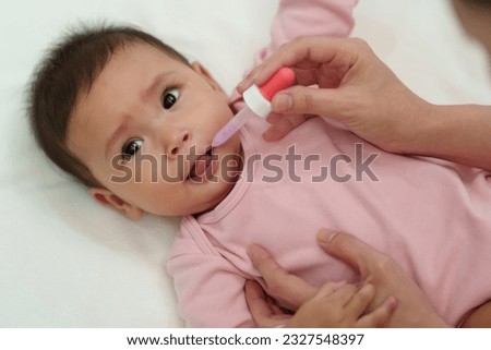mother feeding a liquid medicine to sick infant baby with dropper