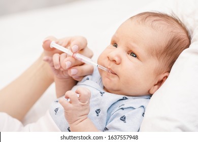 Mother feeding newborn baby with Vitamin K using plastic syringe to prevent Vitamin K deficiency bleeding (VKDB) known as Haemorrhagic disease of the newborn