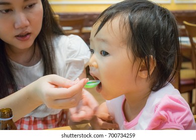 Mother Is Feeding Syrup Medicine To Her Child.