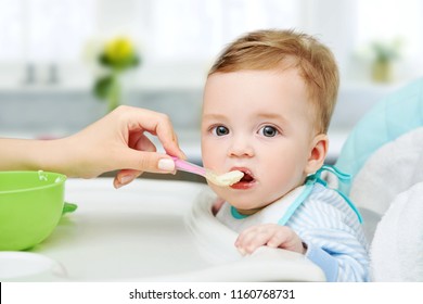 Mother Feeds Baby In The Kitchen With Baby Food