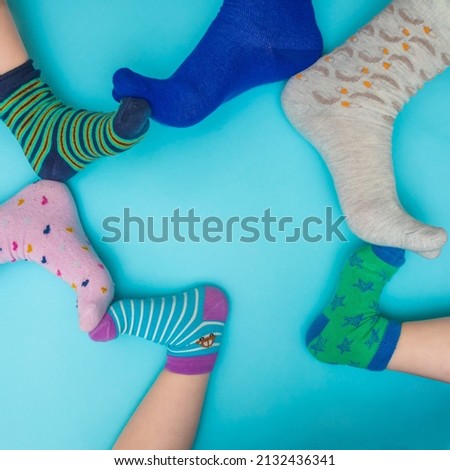 Mother and child’s feet touch on a light blue background with odd socks of different colors. Family creative minimal concept. Down Syndrome awareness month. 21. of March. Copy space.