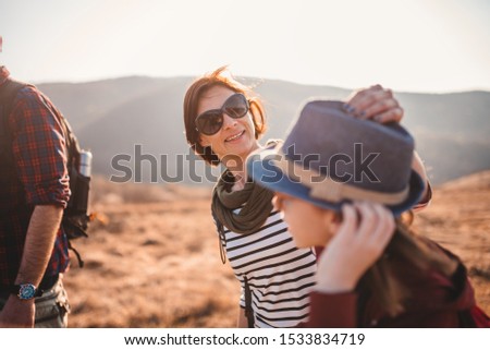 Mother fixing her daughter hat while they hiking on a mountain