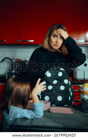 
Mother Forgetting to Pack Something for the Kid School Bag
Tired mom helps daughter to get ready for preschool