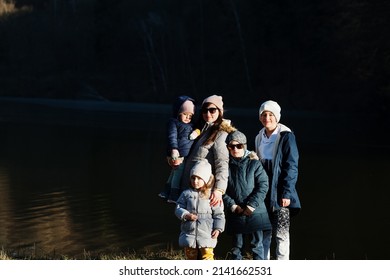 Mother With Four Kids In Pound At Early Spring Park.